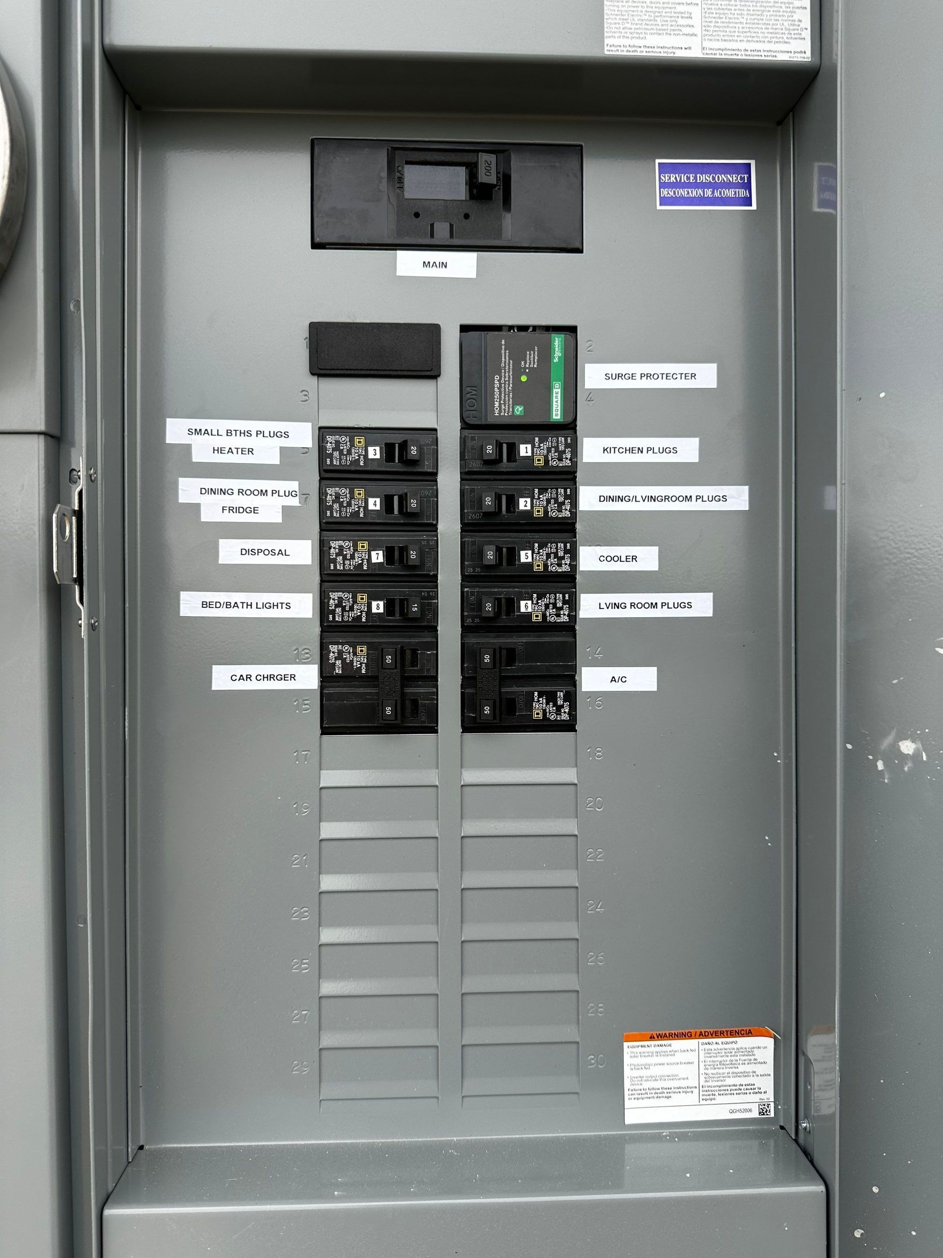 Electrical circuit breaker panel with labeled switches and warning labels in a gray utility cabinet