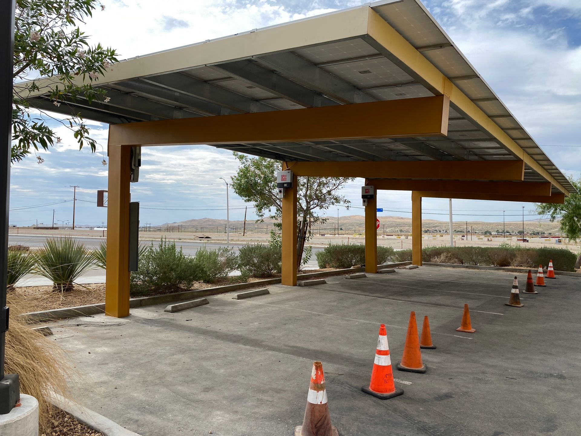 Covered parking structure with orange cones on a paved lot near the waterfront