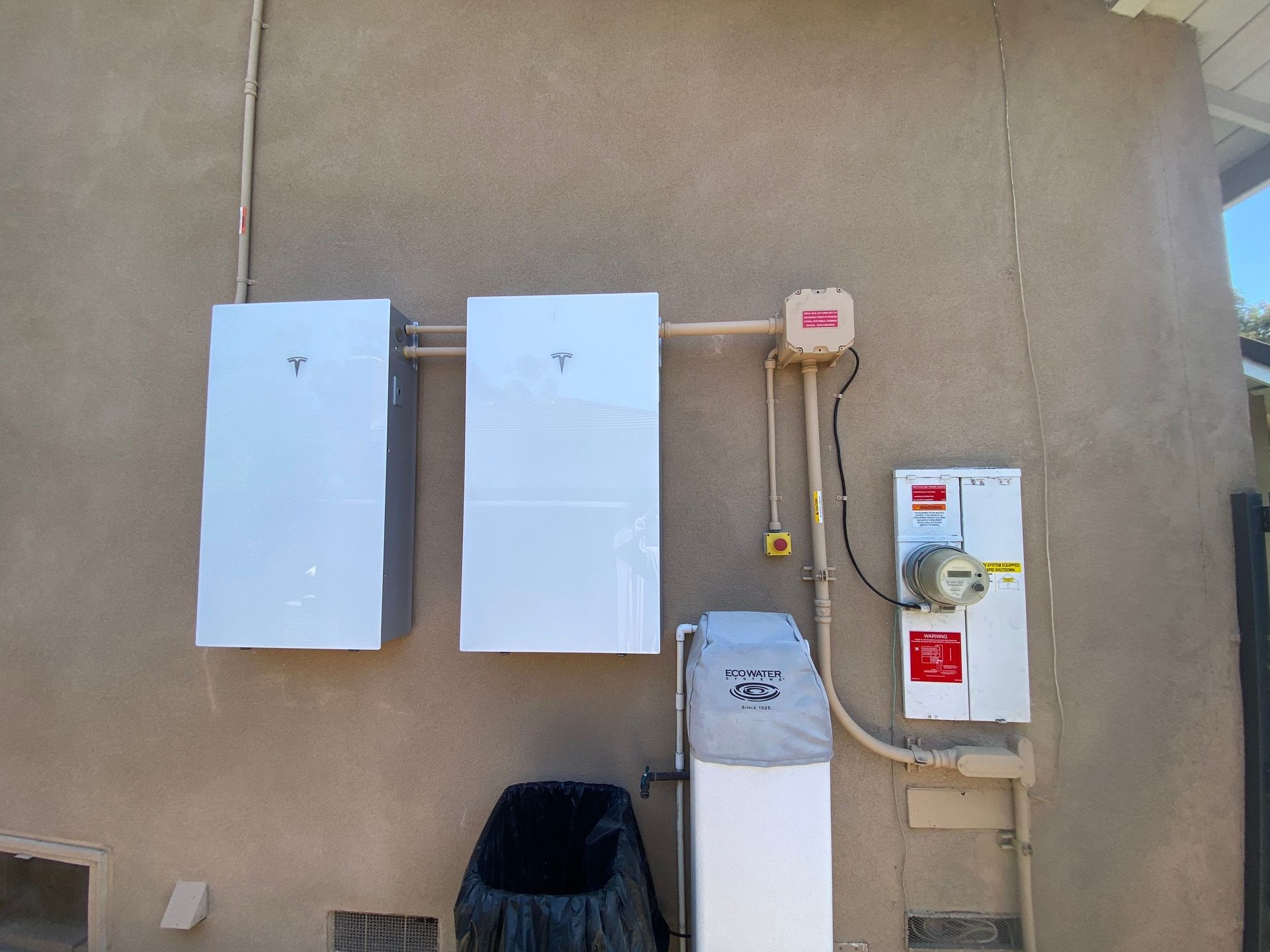 Utility meters and electrical boxes mounted on a beige exterior wall.