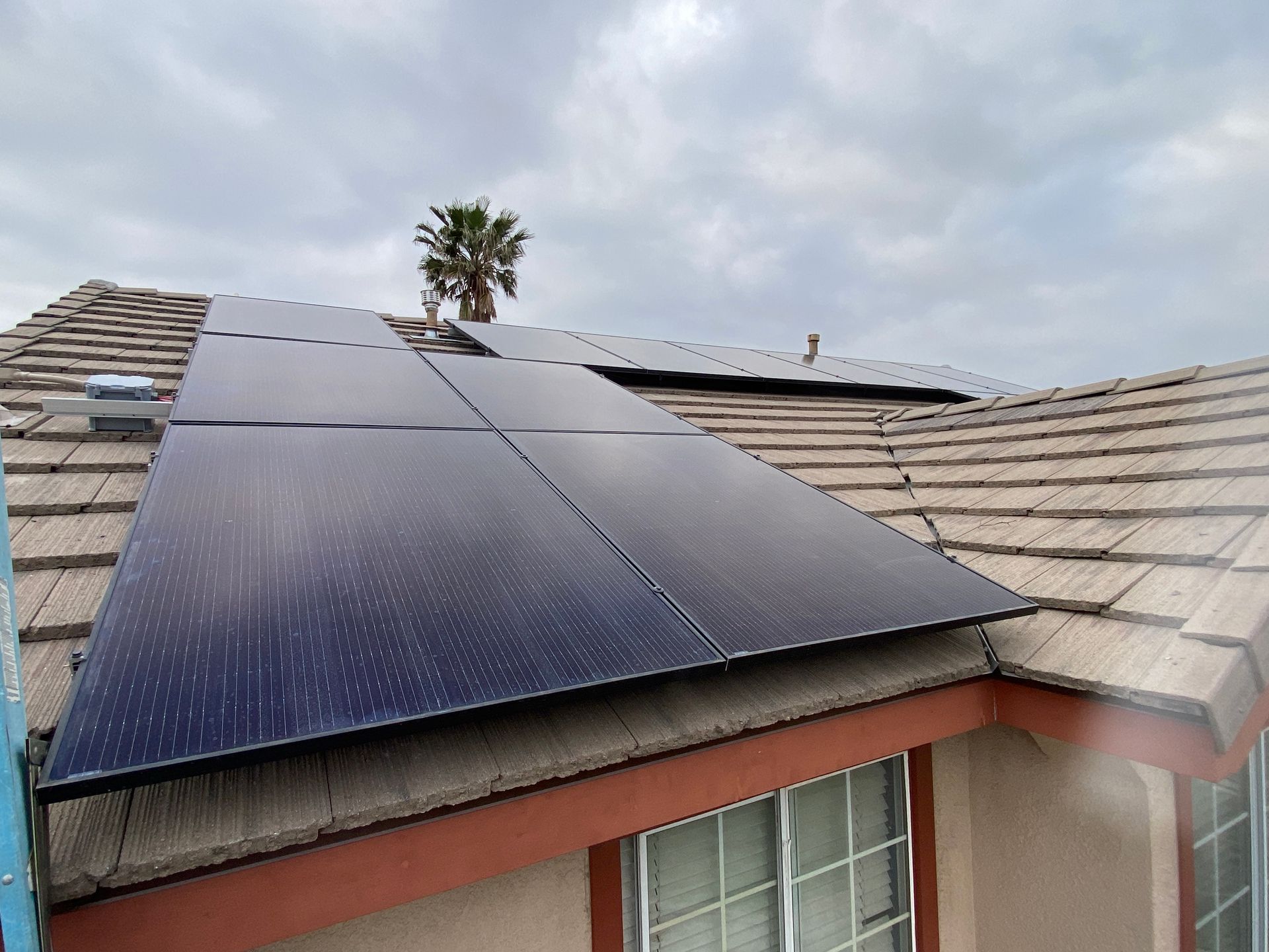 Solar panels installed on a rooftop under a cloudy sky.