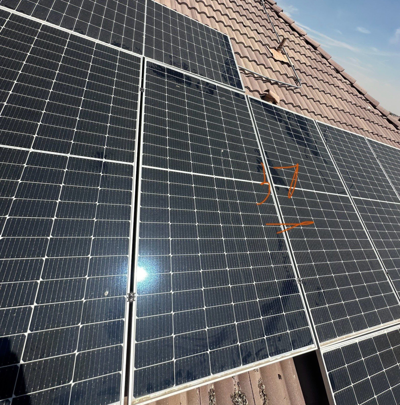Solar panels mounted on a tiled roof under bright sunlight