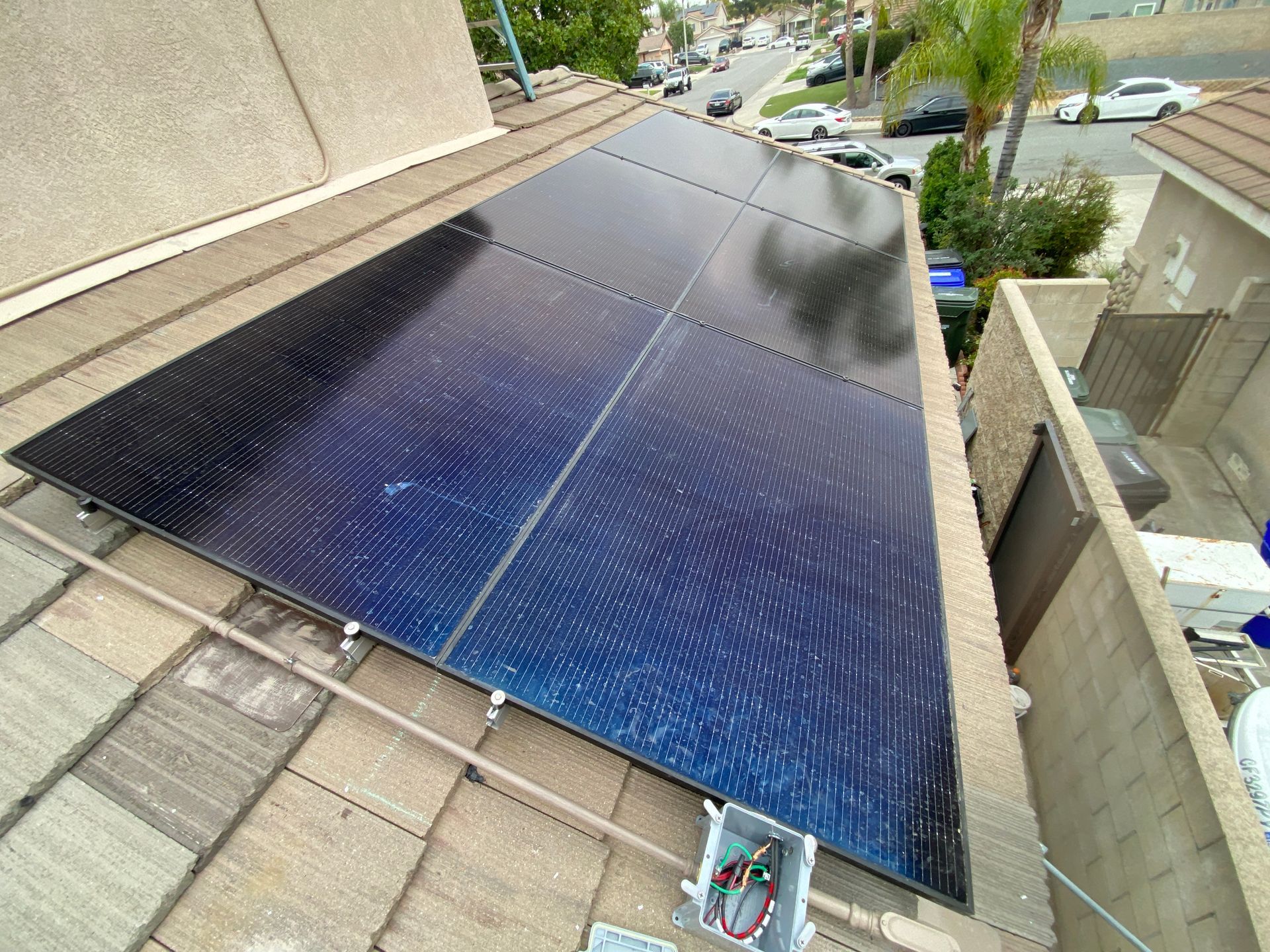 Solar panels installed on a sloped roof beside a residential street.