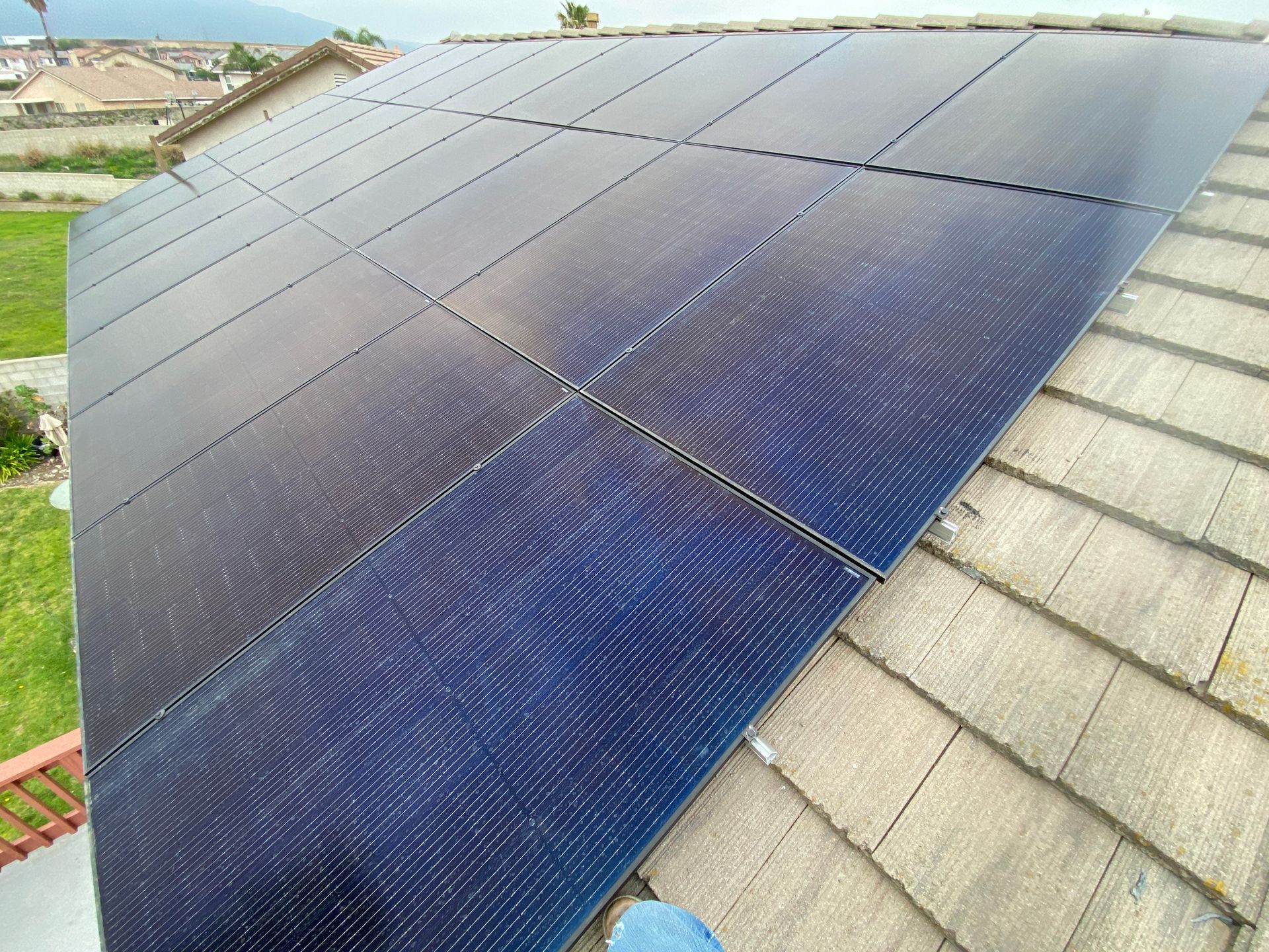 Solar panels mounted on a sloped roof beside gray shingles