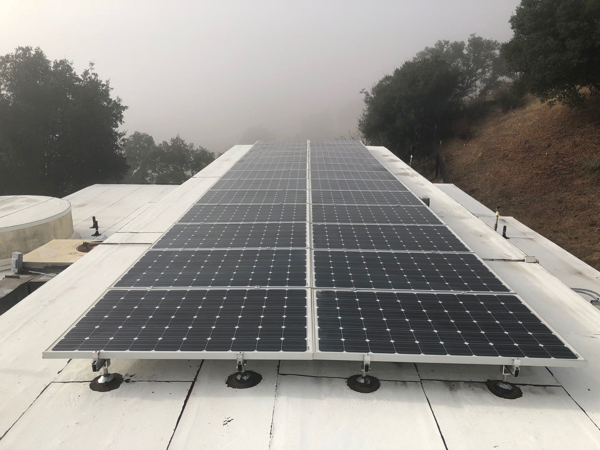 Solar panels installed on a sloped rooftop in a foggy outdoor setting