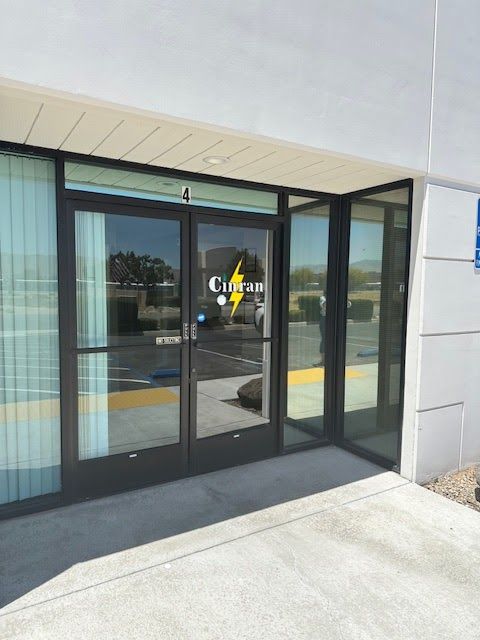 Storefront entrance with glass doors and a black frame under a white overhang.