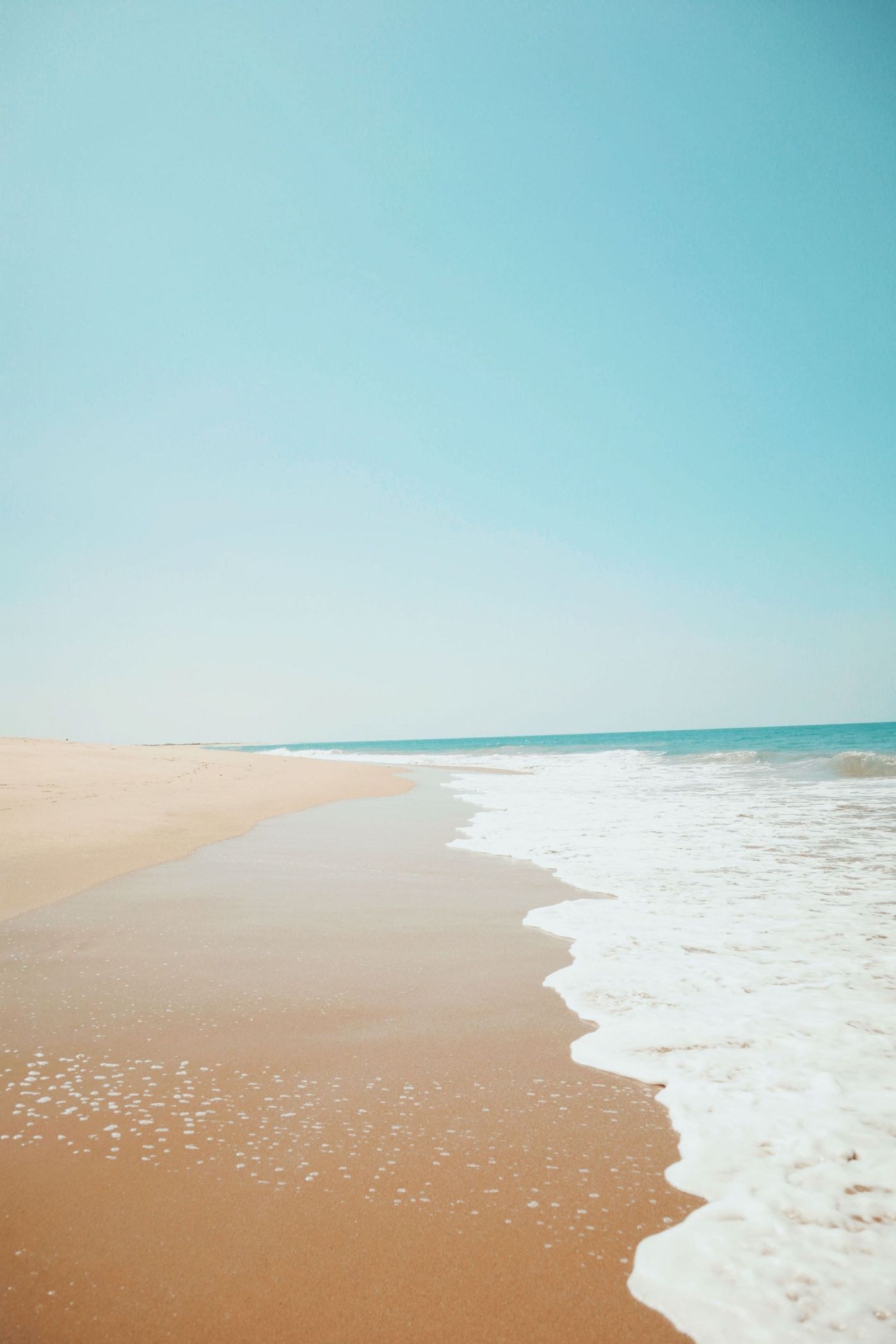 Quiet sandy beach with turquoise water and a clear blue sky