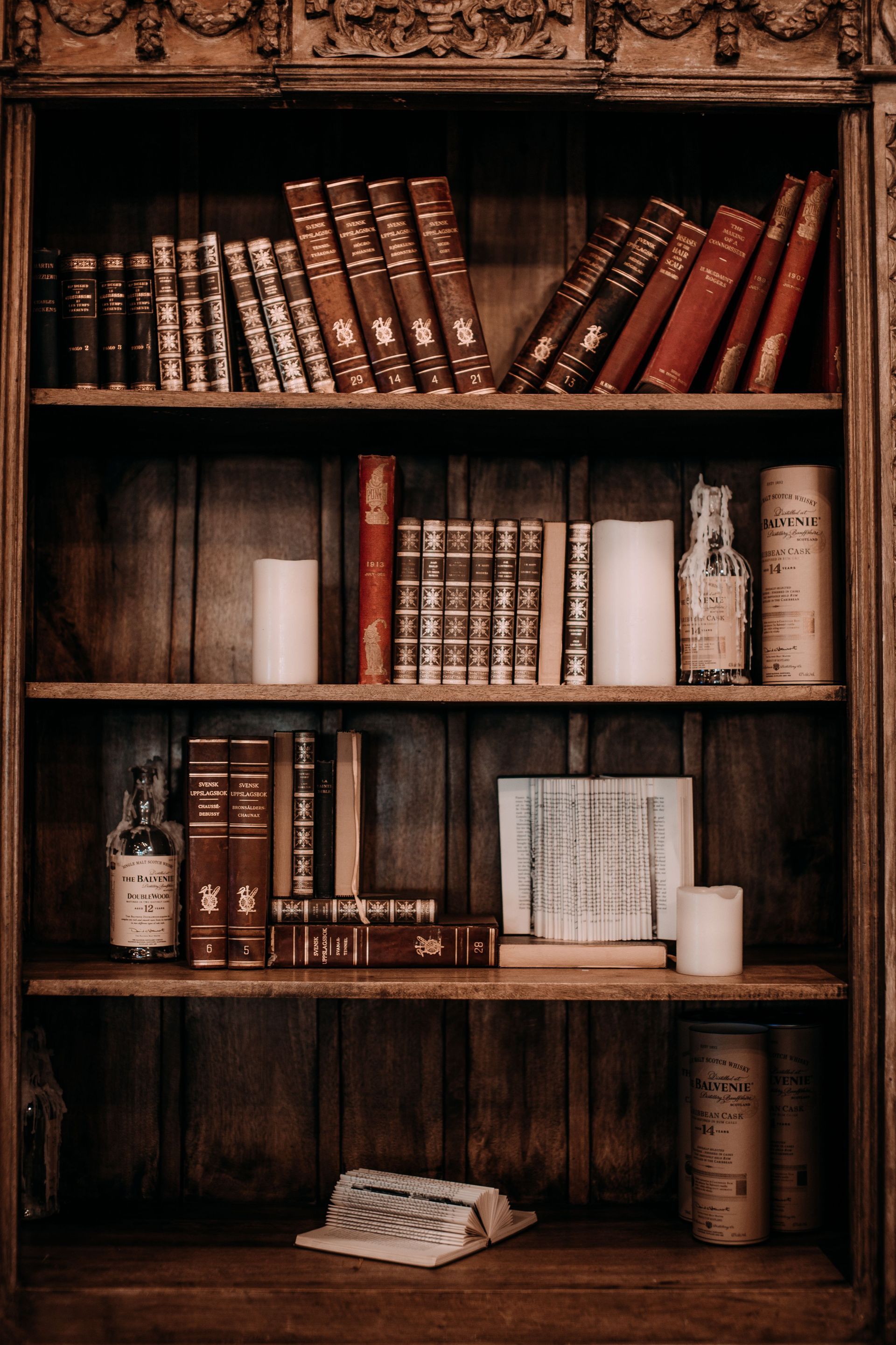 Wooden bookshelf with vintage books and candles in a warmly lit room