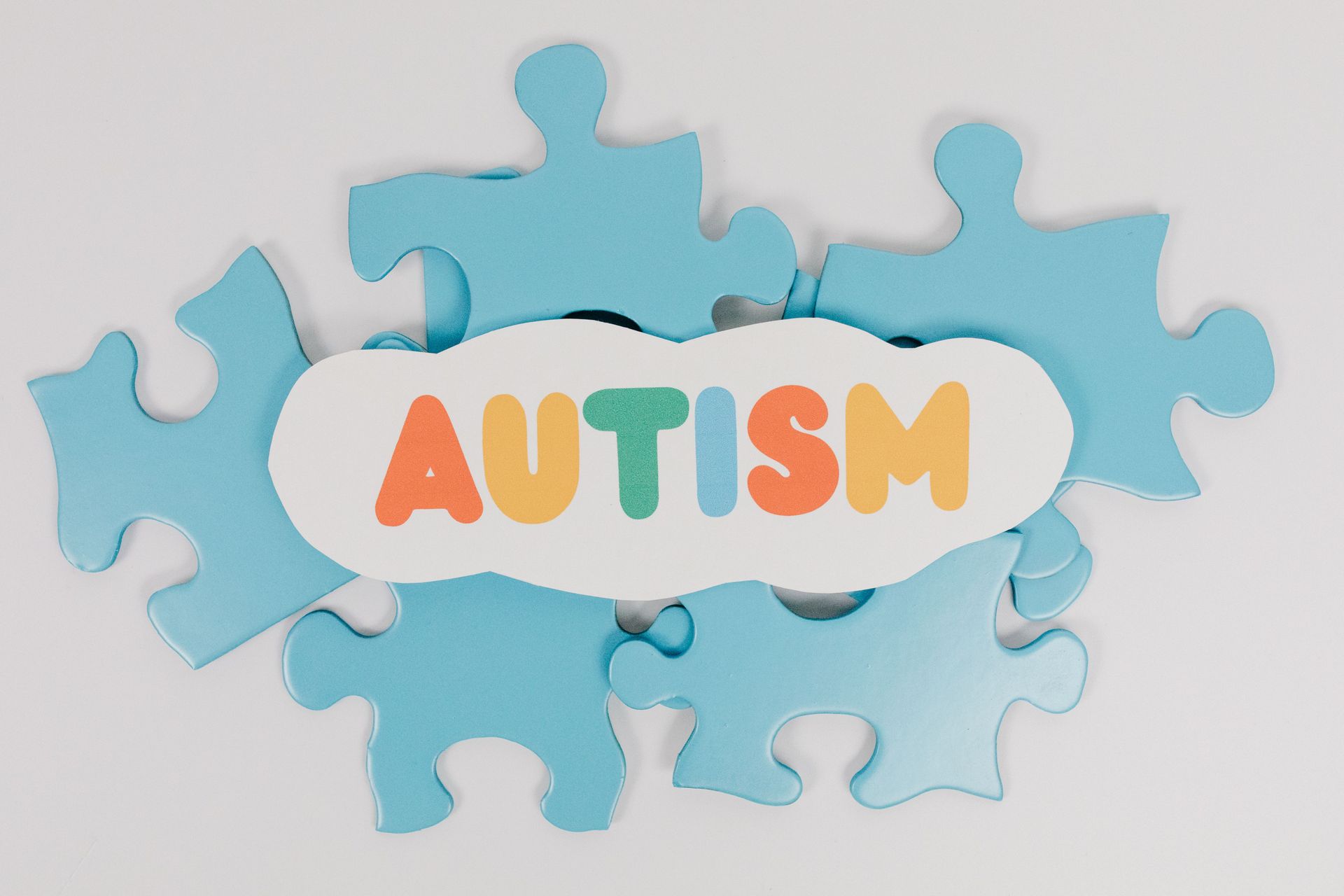 Blue puzzle pieces with the word “AUTISM” in colorful letters on a white background