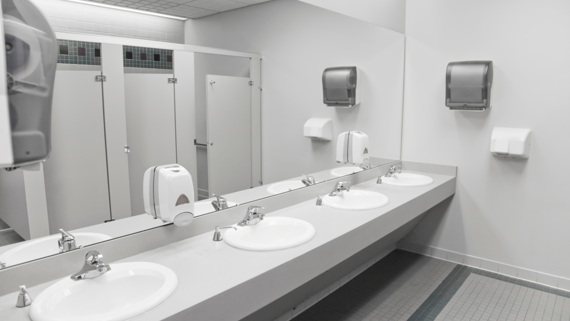 Clean public restroom with mirrors, double sinks, and wall-mounted paper towel dispensers