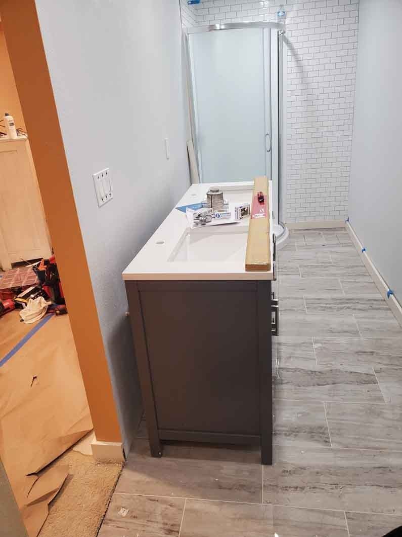 Hallway with a dark vanity cabinet, white countertop, and gray wood-look flooring in a home interior