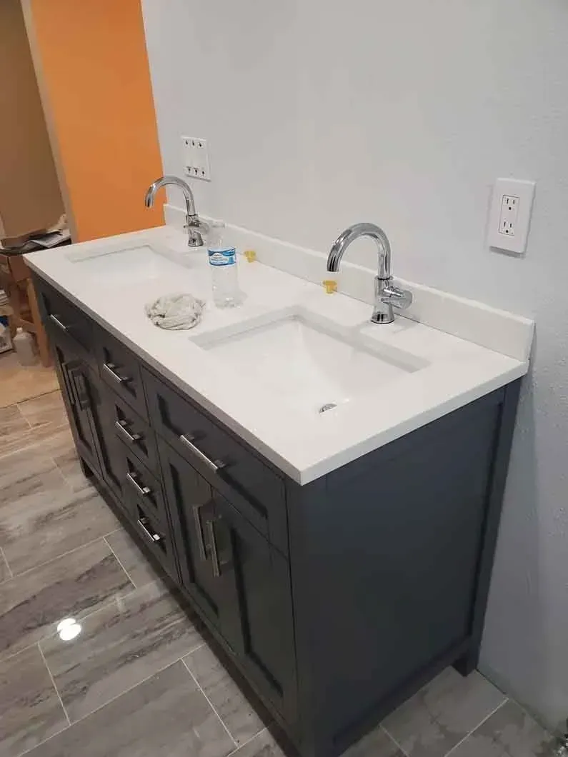Bathroom vanity with white sink and dark cabinets against a light gray wall