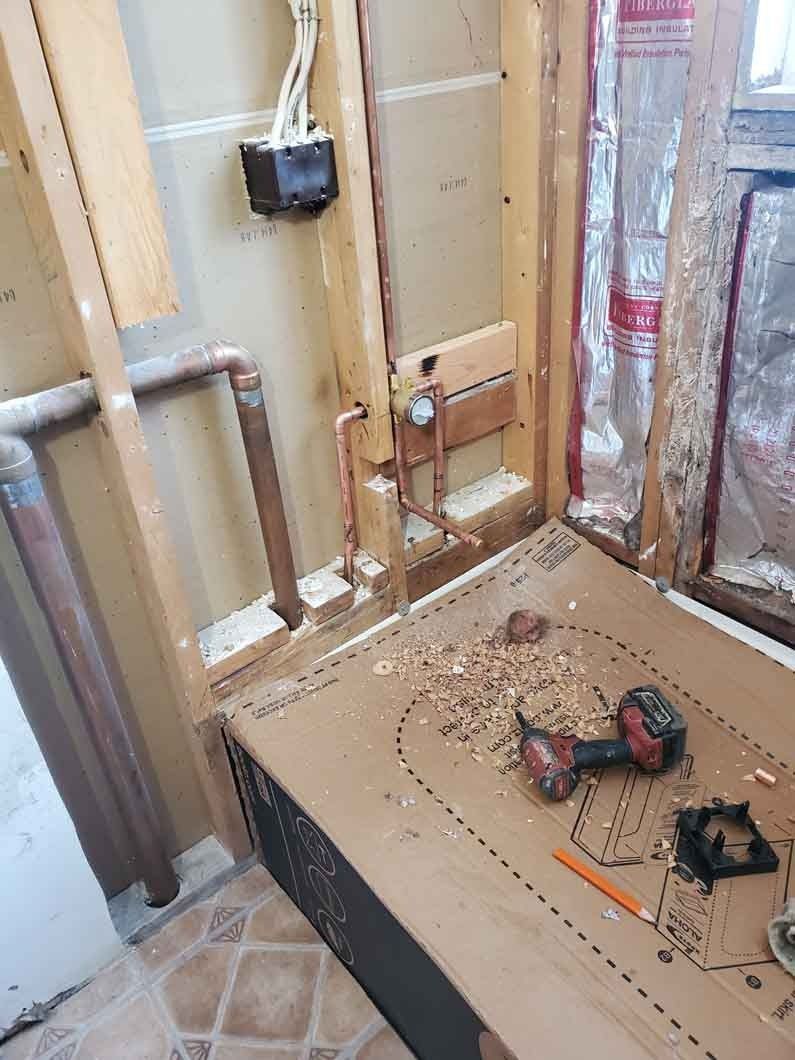 Partially renovated room with exposed walls, insulation, and tools on the floor