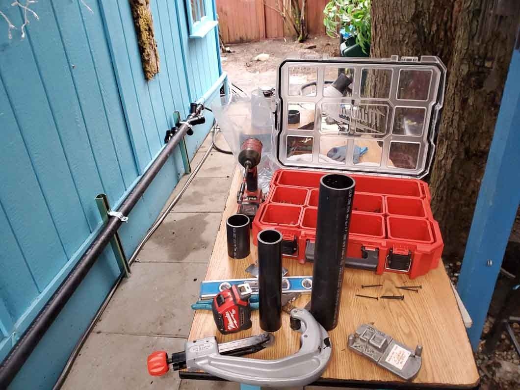 Tools and parts laid out on a wooden workbench in a narrow outdoor corridor.
