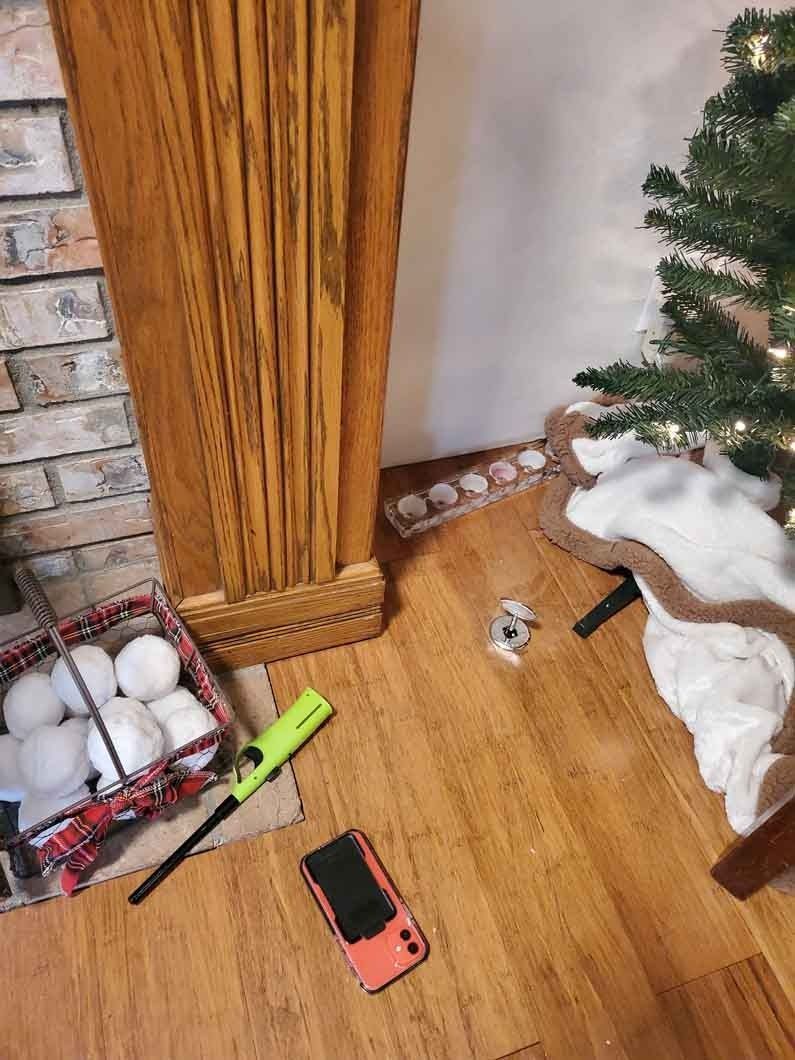 Red phone on wood floor beside a Christmas tree, candles, and a fireplace.