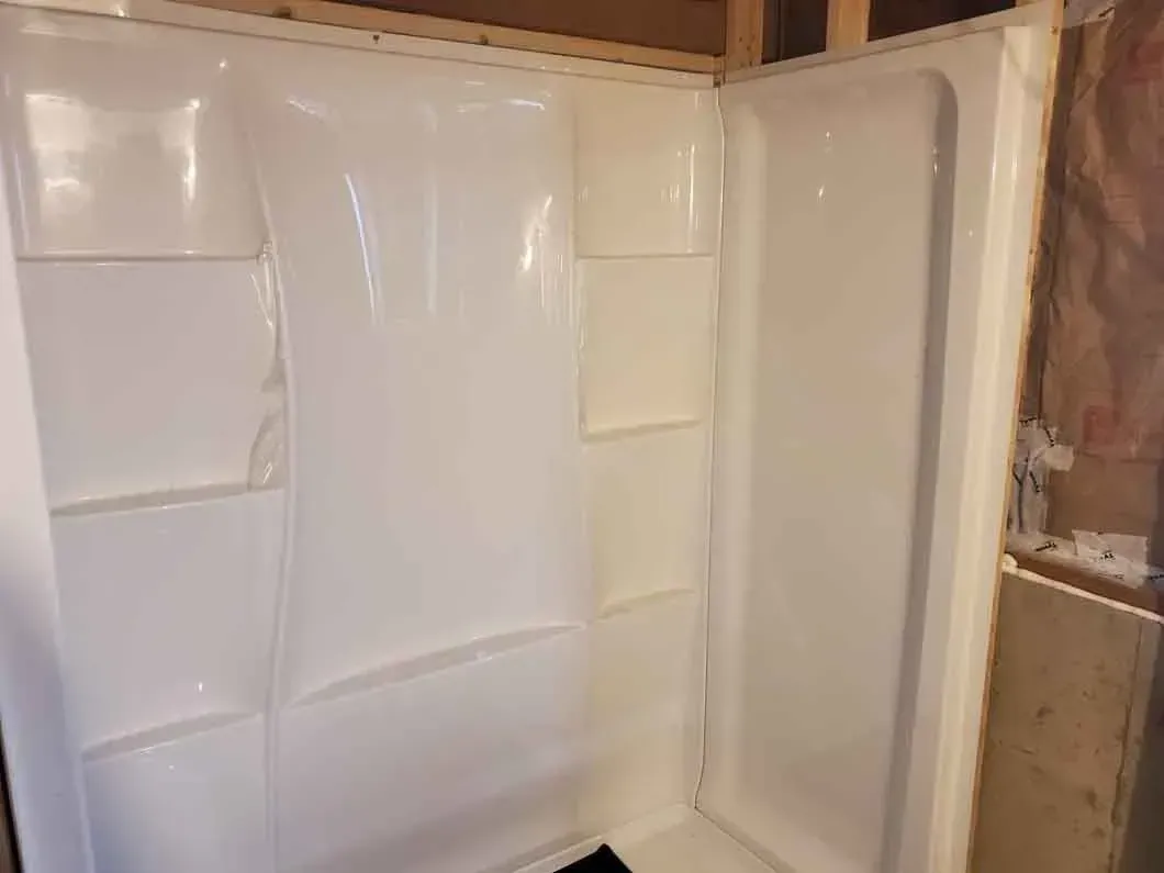 White shower or tub insert with built-in shelves in a bathroom under construction