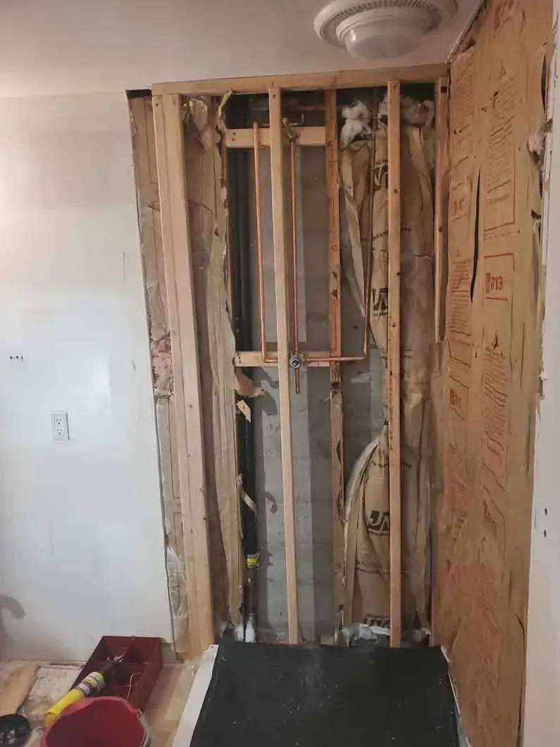 Partially gutted wall with exposed studs and insulation in a room under renovation