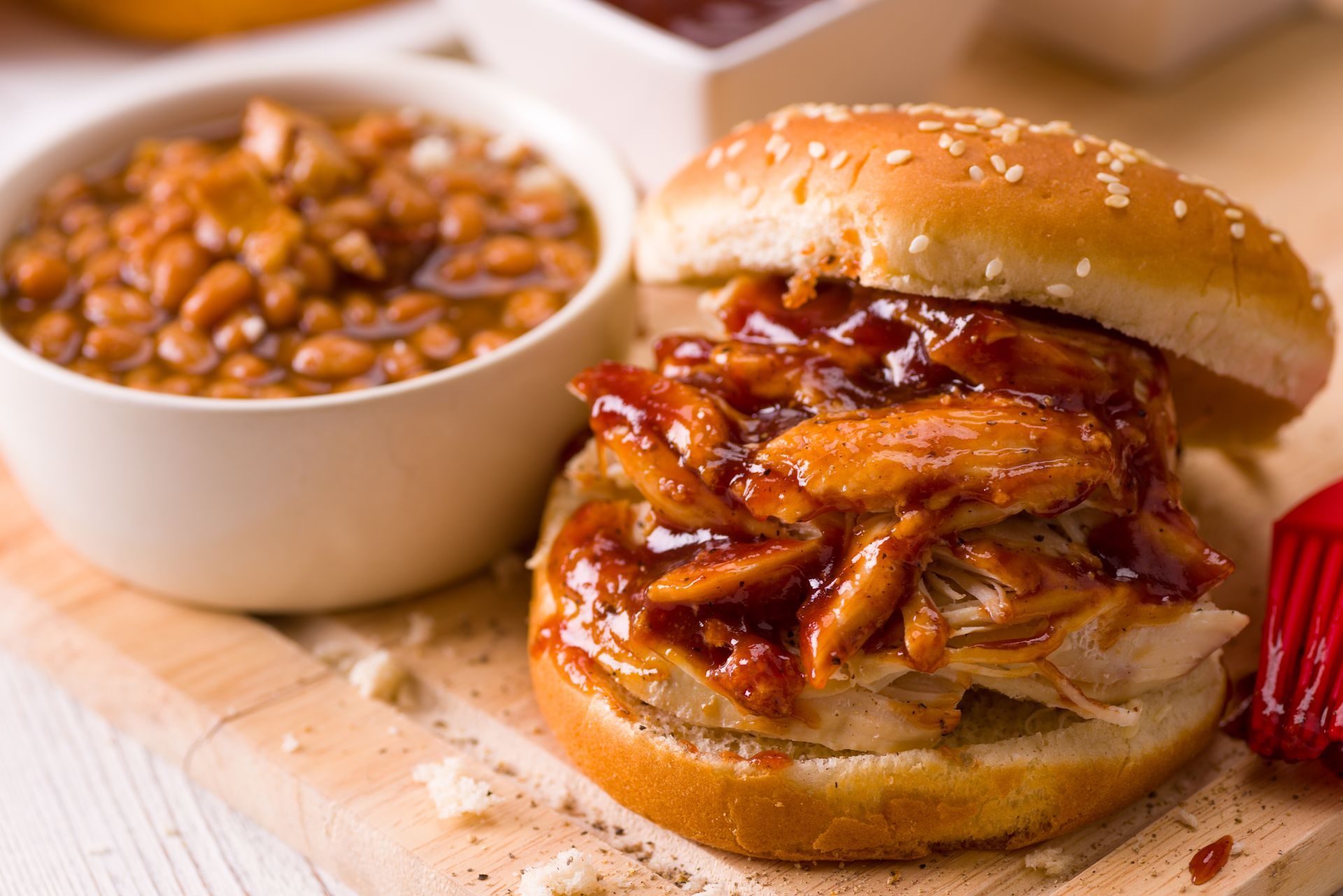 Pulled pork sandwich with barbecue beans on a wooden board