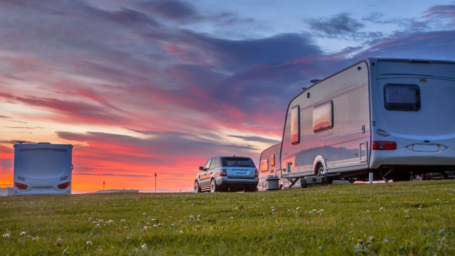 RVs parked in a grassy field at sunset under a colorful pink and purple sky