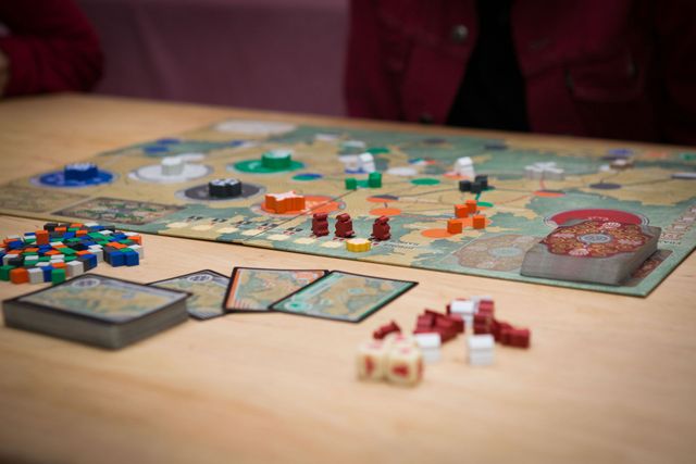 Board game spread on a table with colorful pieces, cards, and tokens in play