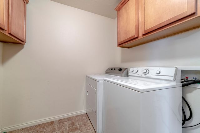 Laundry room with white washer and dryer beneath wood cabinets