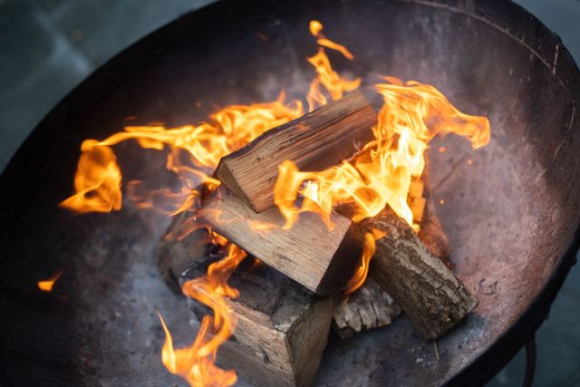 Logs burning in a fire pit with bright orange flames