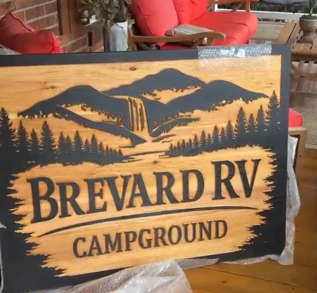Wooden sign reading “Brevard RV Campground” with mountain and pine tree silhouette