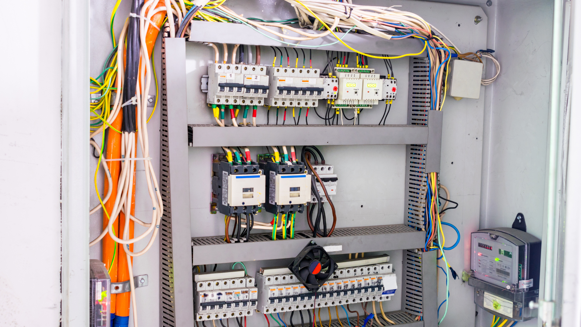 An electrical control panel with various breakers, relays, and organized wiring mounted inside a gray metal enclosure.