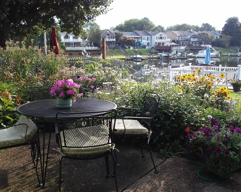 A patio with a table and chairs surrounded by flowers.