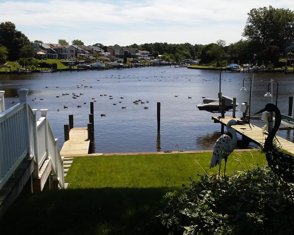 A statue of a bird stands on a dock overlooking a body of water.