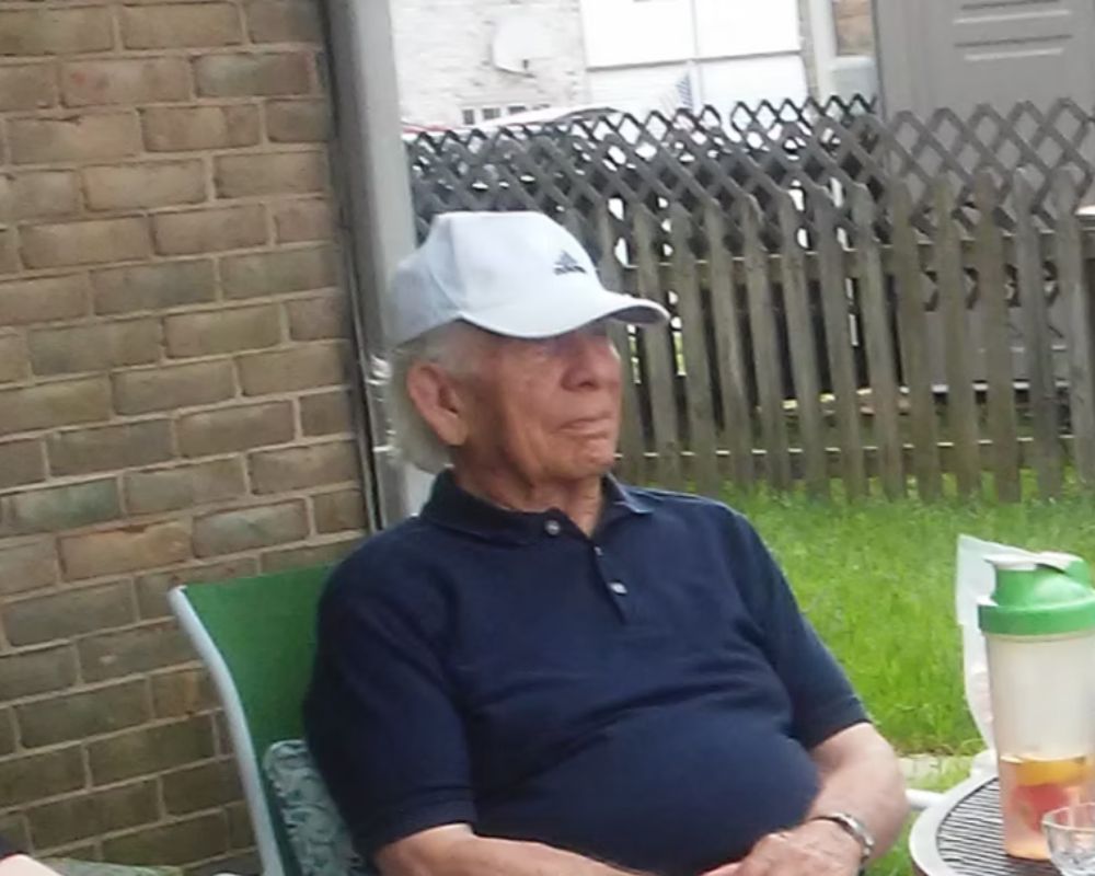 Rob wearing a white hat is sitting in a chair.