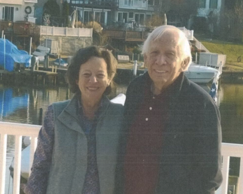 Rob and Jane posing for a picture in front of a lake.