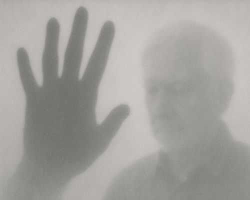 A person 's hand is visible behind a foggy glass.