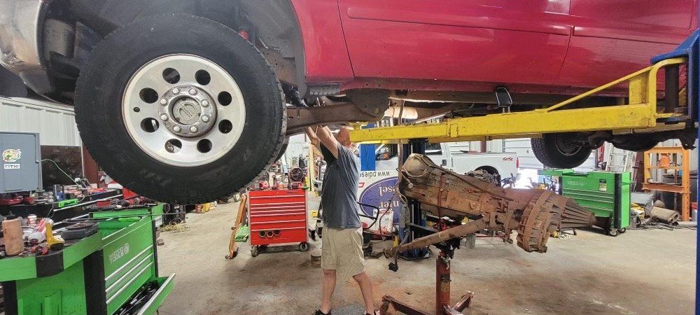 A red truck is sitting on a lift in a garage.