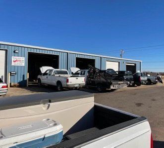 A row of trucks are parked in front of a garage.