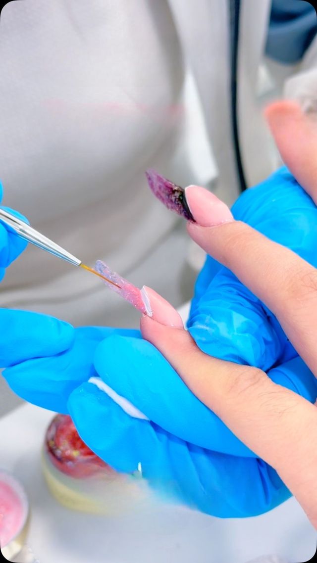 Una donna che indossa guanti blu si sta facendo smaltare le unghie