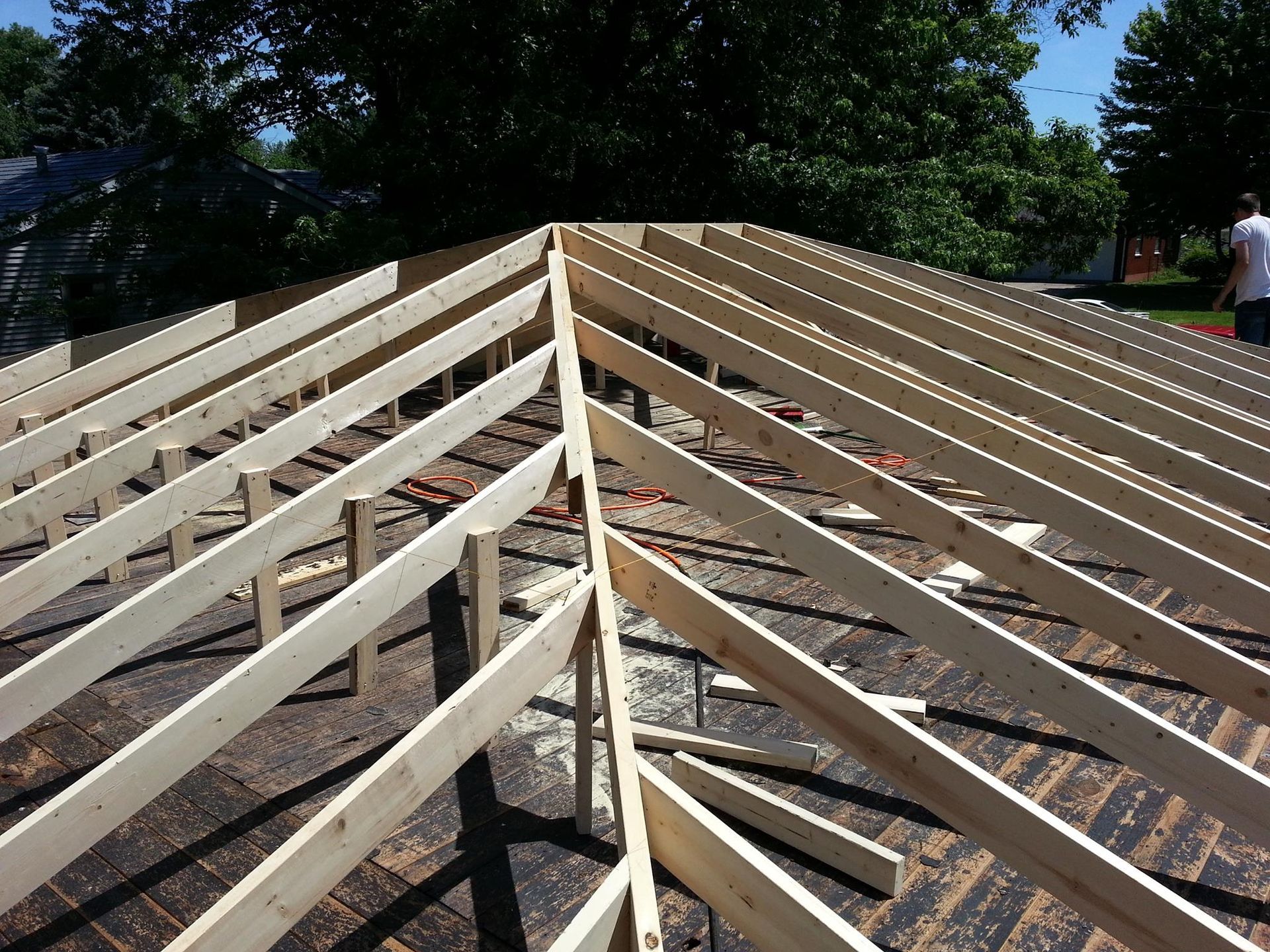 Wooden rafters being installed to frame a roof hip on a construction site.