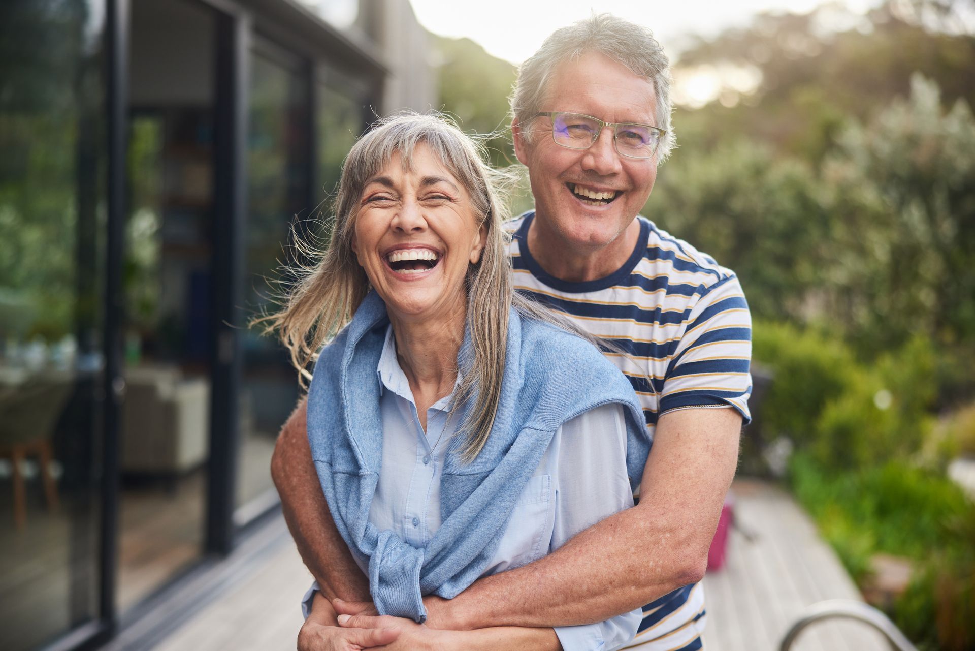 Smiling older couple embraces outdoors.