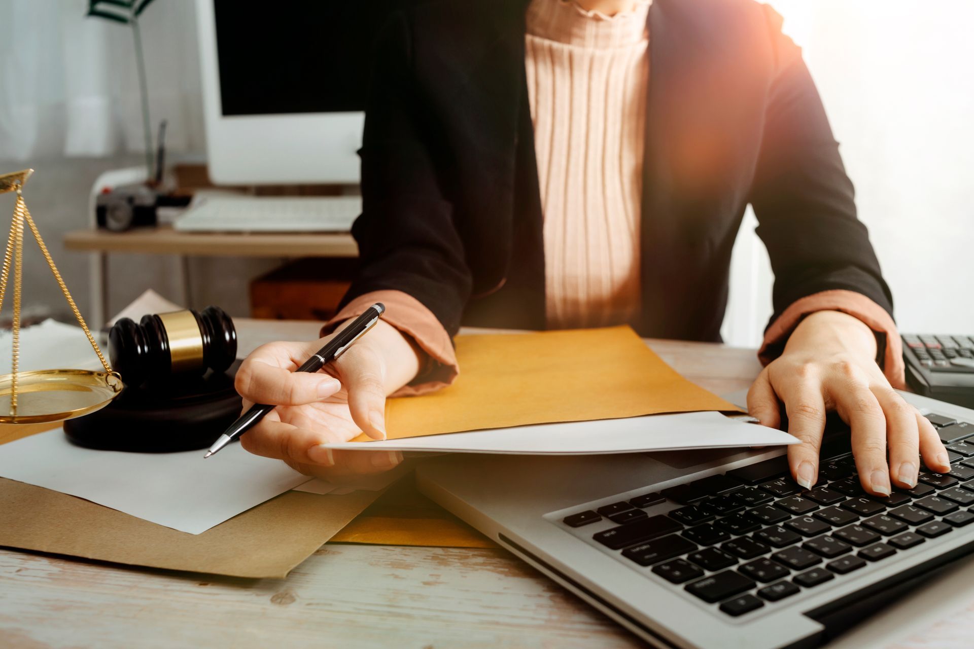 Lawyer reviewing documents at a desk with a laptop and scales of justice Lawyer reviewing documents at a desk with a laptop and scales of justice