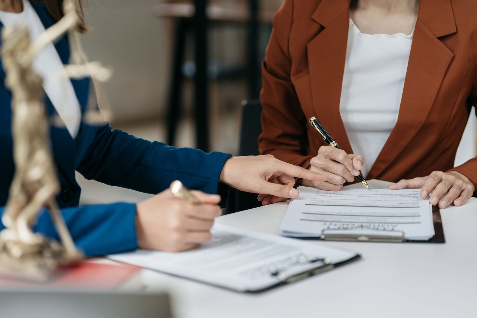 People signing documents at a meeting table with clipboards and pens People signing documents at a meeting table with clipboards and pens