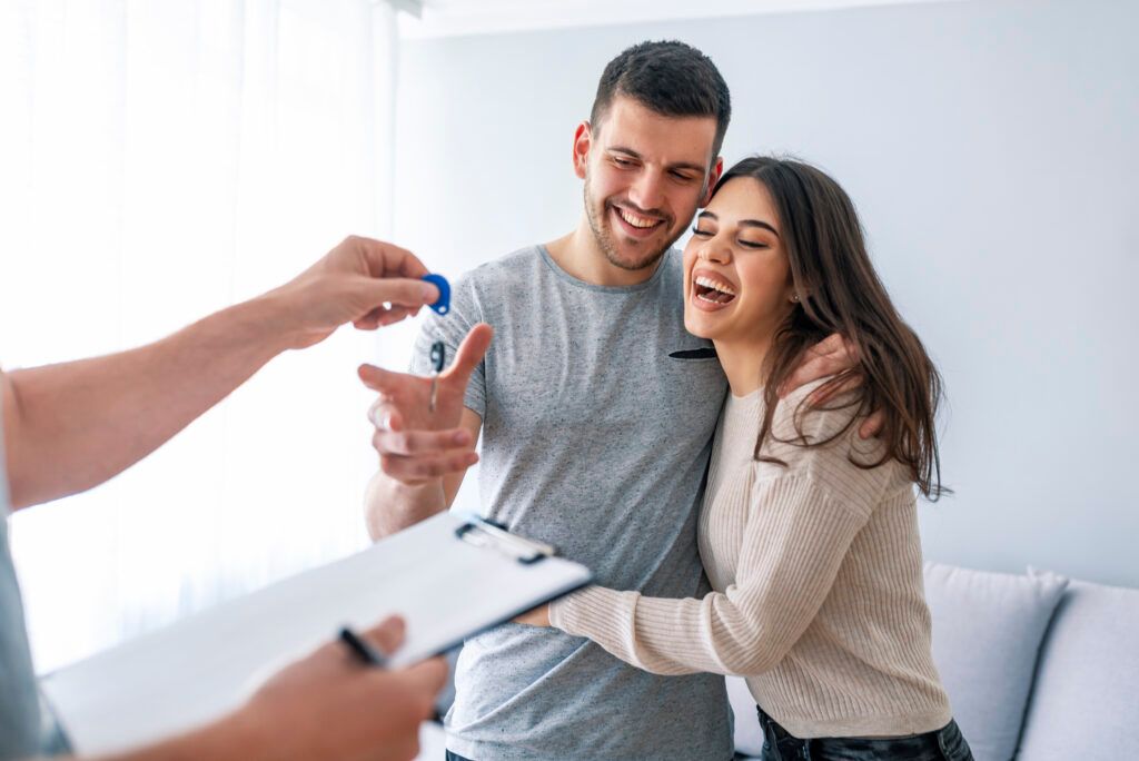 Smiling couple receiving keys from a realtor in a bright living room