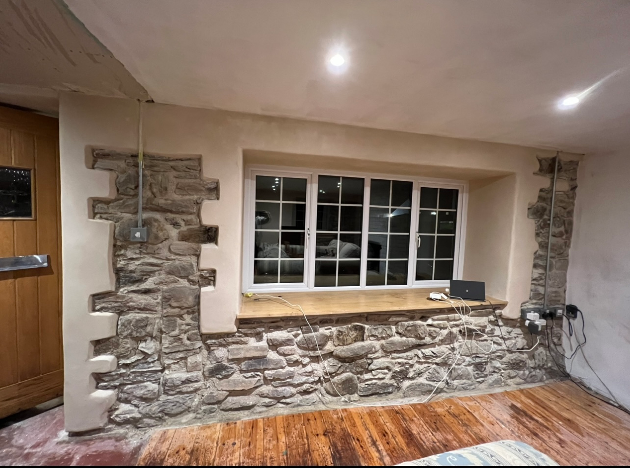 A living room with a stone wall and a window.