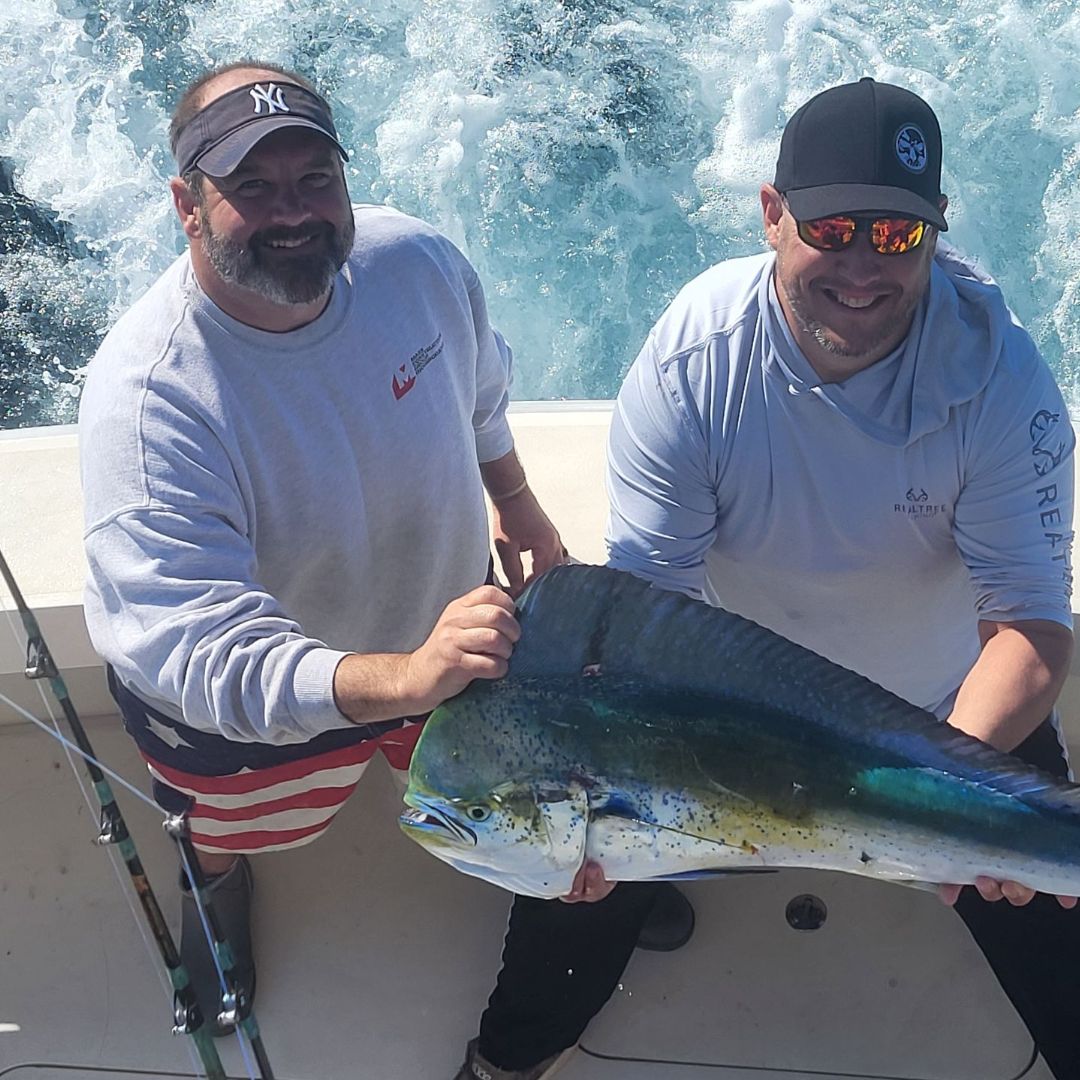 Captain Michael assisting an Angler who reeled in an impressive Mahi Mahi