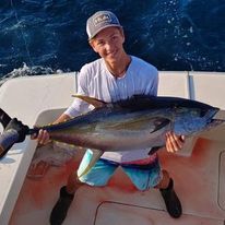 A young man is holding a large fish on a boat.