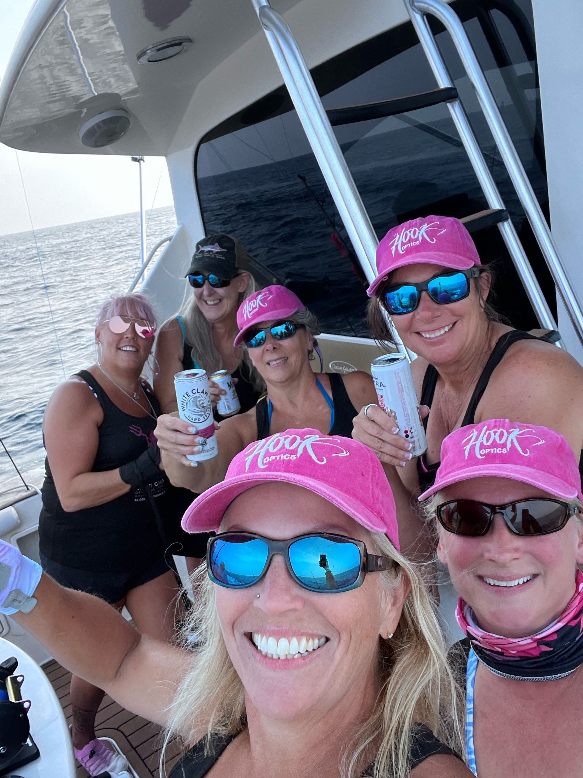 A group of women wearing pink hats and sunglasses on a boat