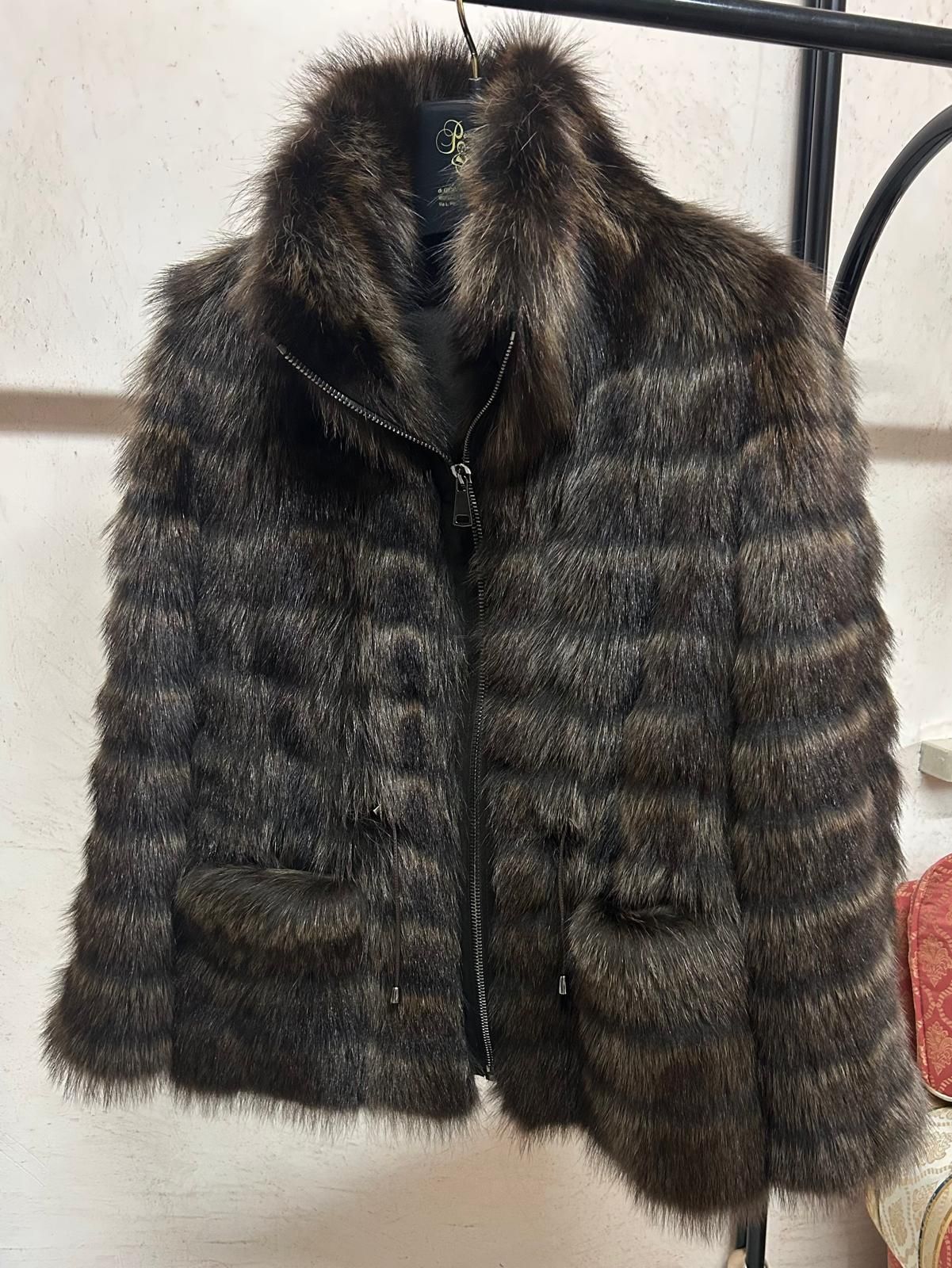 Cappotto di pelliccia marrone scuro a righe orizzontali appeso a un appendiabiti