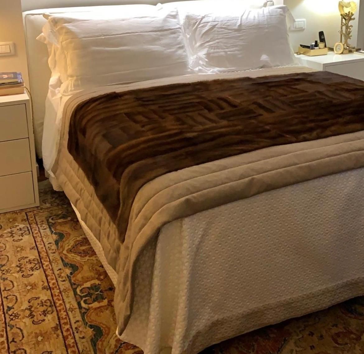 Un letto ben rifatto con cuscini bianchi, coperta marrone e trapunta beige in una camera da letto accogliente.