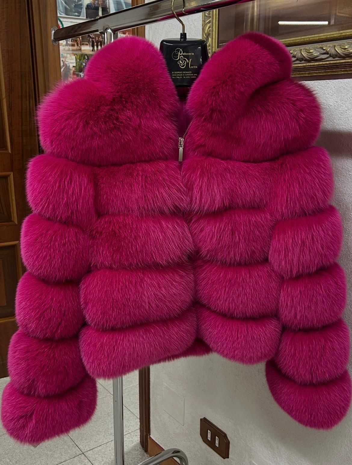 Giacca imbottita color magenta appesa a una gruccia in un negozio.