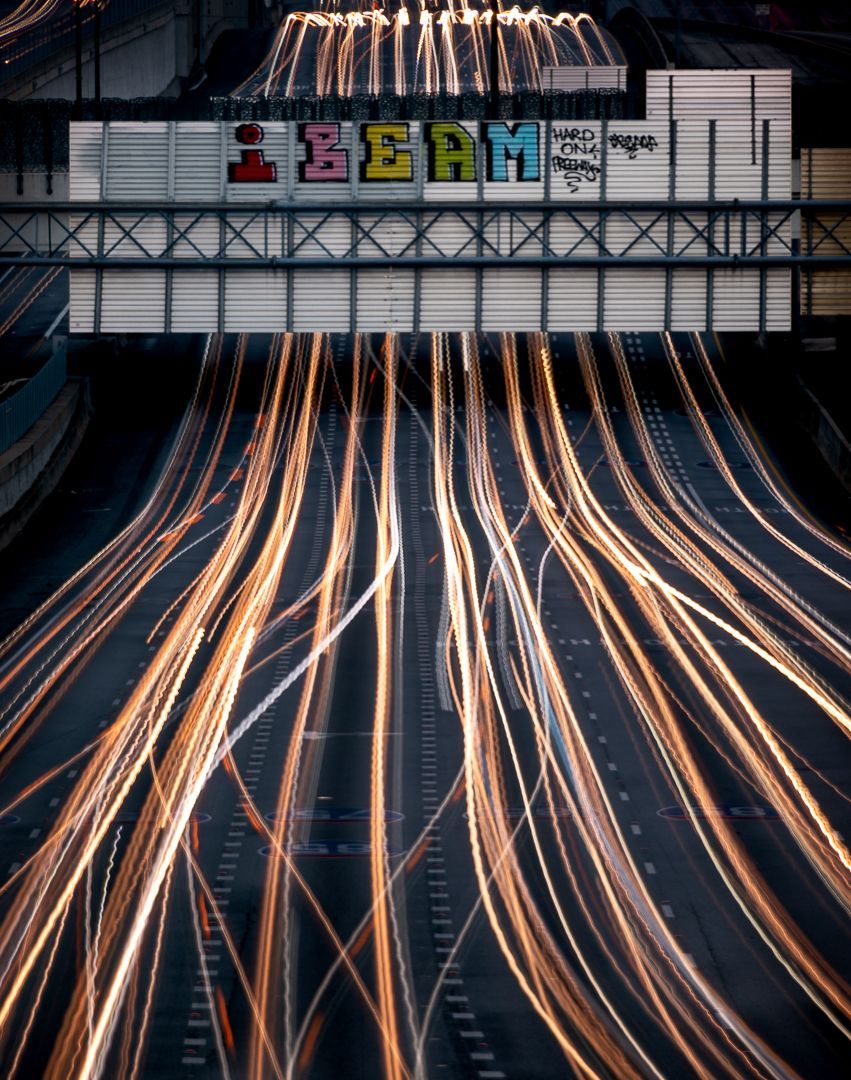 A long exposure of city traffic racing under a street sign with the word iBeam written on it via graffiti.  Brad Burgess Photography, Talking Excitingly