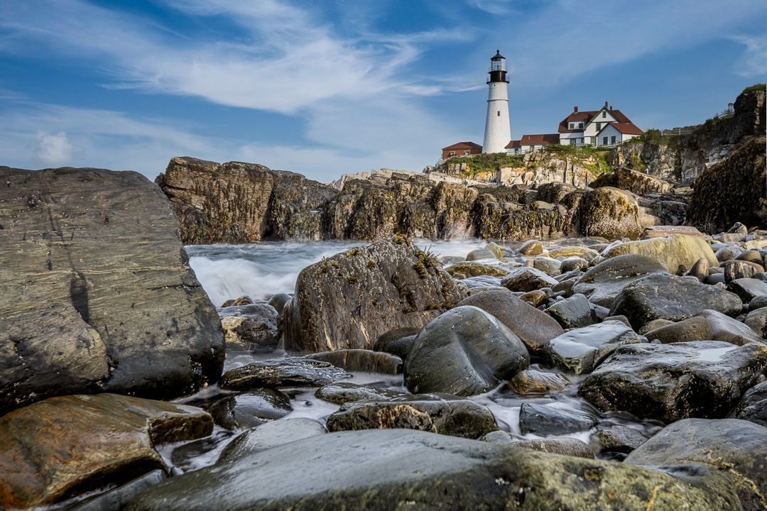 a lighthouse is sitting on top of a rocky cliff next to the ocean . Portland Head Light, Talking Excitingly, Brad Burgess Photography