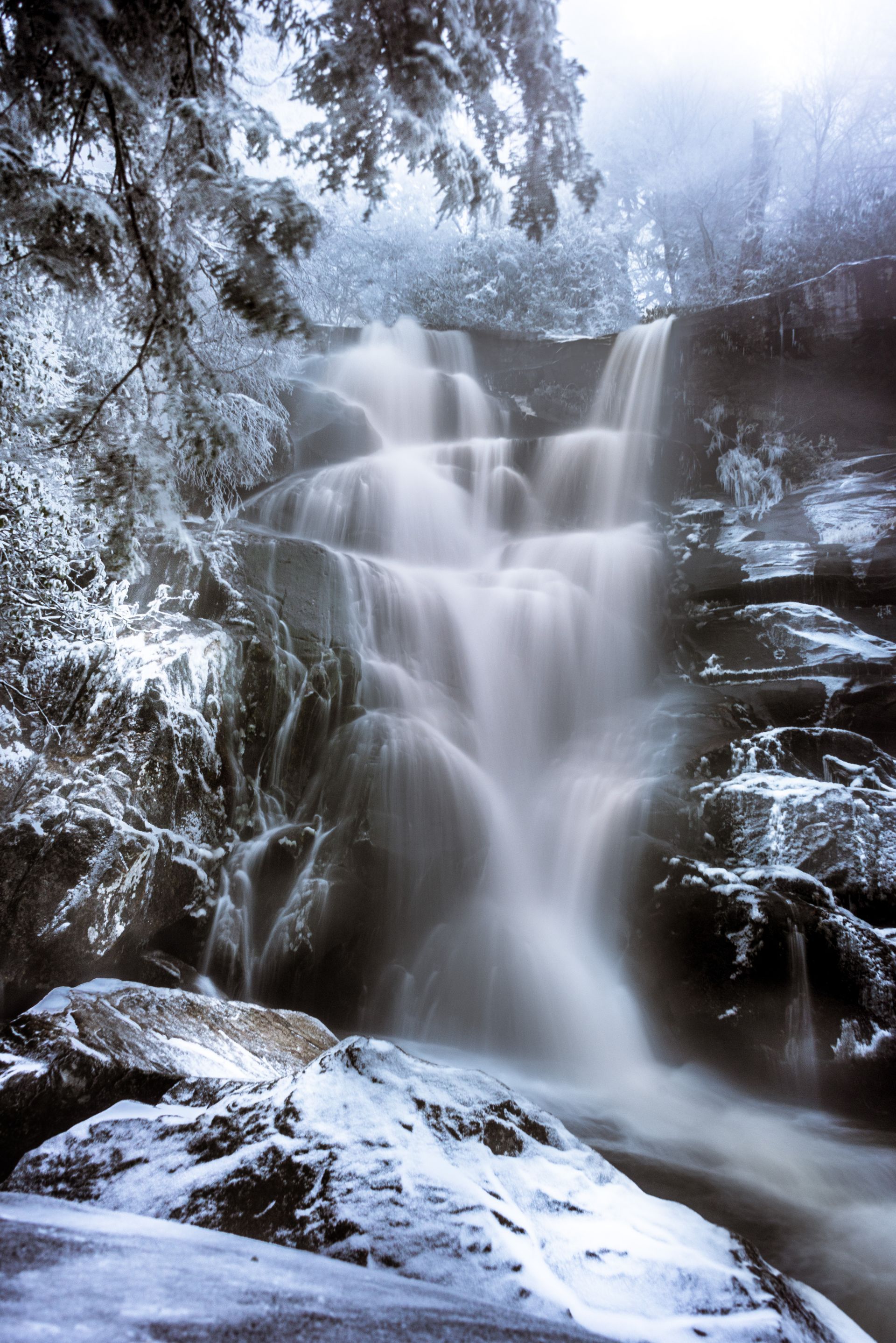 Ramsey Cascade waterfall is surrounded by snow-covered rocks and trees in Smoky Mountain National Park. Talking Excitingly, Brad Burgess Photogrpahy